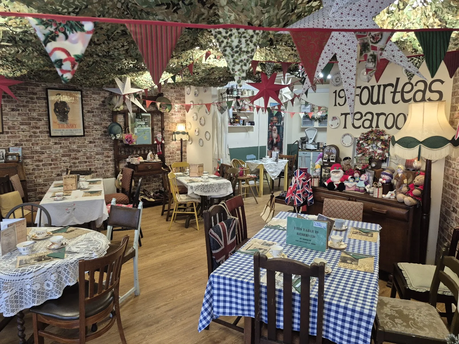 The main room at 19 Fourteas with the tea room name painted on the wall, bunting and gingham tablecloths